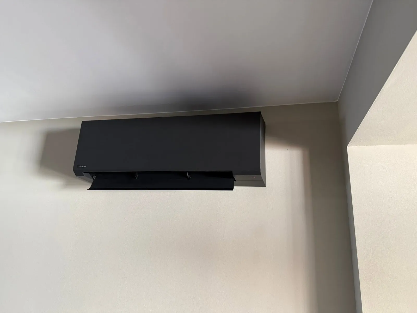 Zwart airco-binnendeel hoog tegen een witte wand