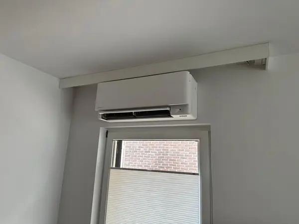 Airco-binnendeel strak gemonteerd boven een raam in een slaapkamer