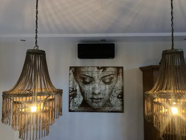 Zwart airco-binnendeel weggewerkt boven een schilderij in een sfeervol interieur