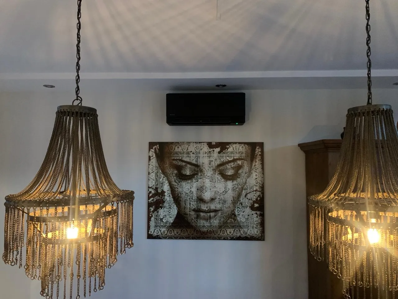 Zwart airco-binnendeel weggewerkt boven een schilderij in een sfeervol interieur