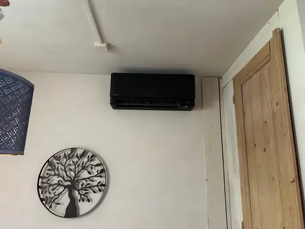 Zwart airco-binnendeel in een landelijk interieur met houten deur