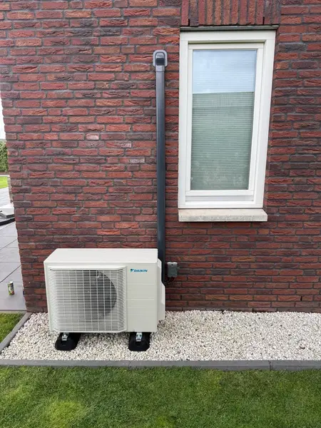 Buitenunit netjes geplaatst op grind naast de gevel van een nieuwbouwwoning
