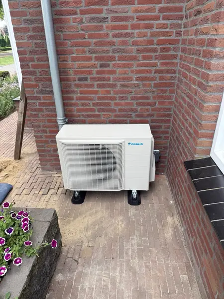 Daikin-buitenunit op trillingsdempers naast een terras