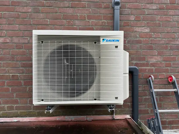 Daikin-buitenunit op wandbeugels tegen een bakstenen gevel