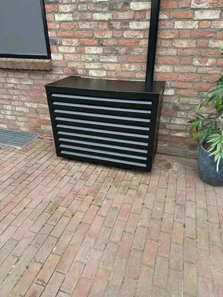 Antracietkleurige omkasting rond een airco-buitenunit op een terras