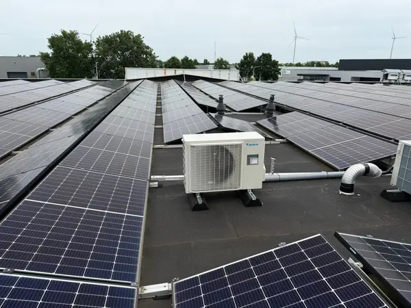 Daikin-buitenunit op het platte dak van een bedrijfspand, tussen de zonnepanelen