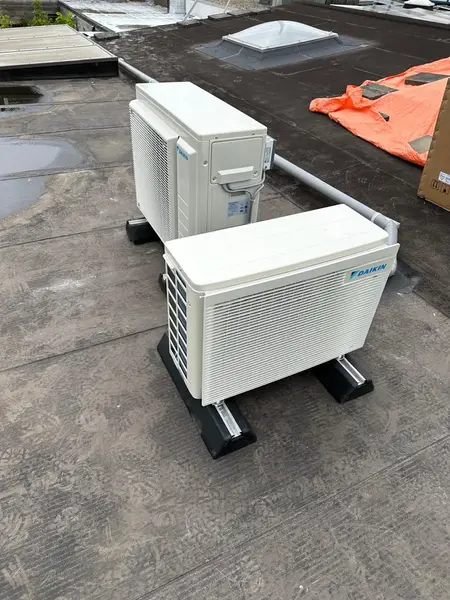 Twee buitenunits op dempers tijdens installatie op een plat dak