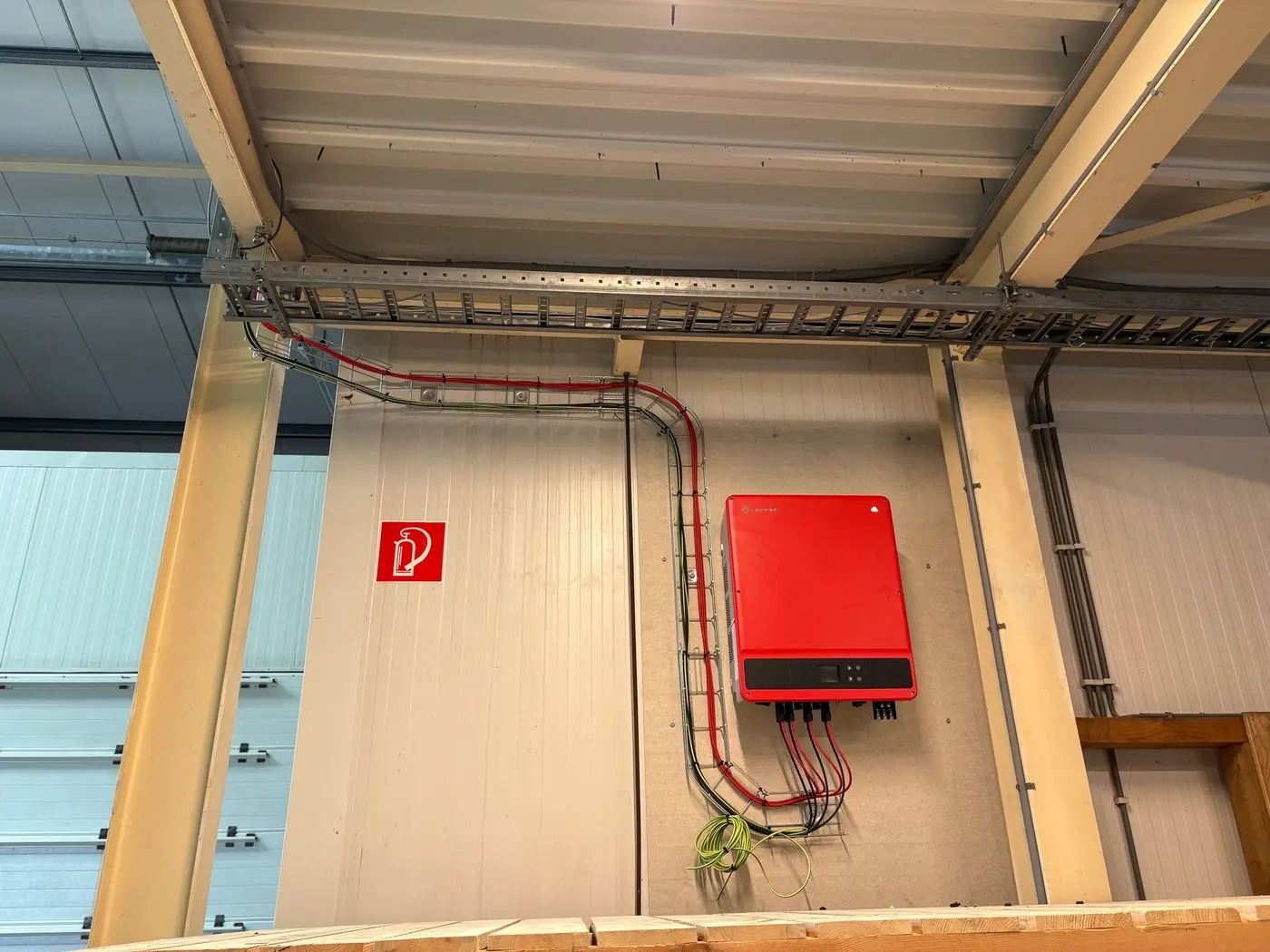 Rode omvormer voor zonnepanelen, strak bekabeld in een bedrijfshal