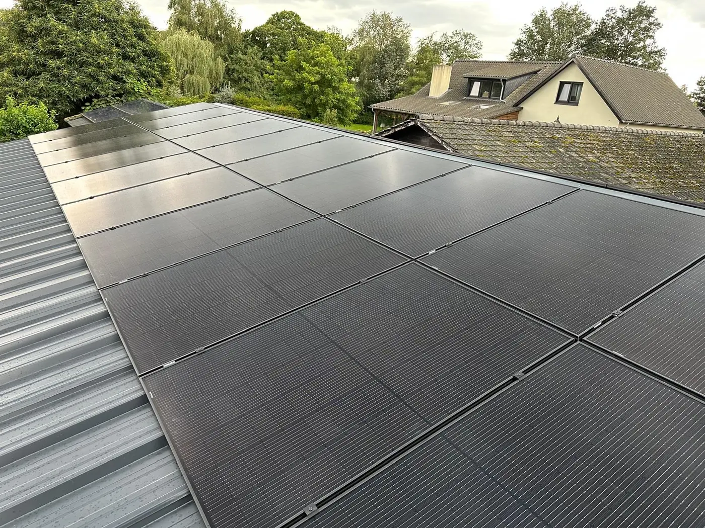 Zonnepanelen op een metalen dak, met de woning op de achtergrond