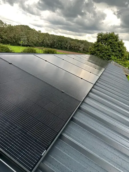 Zwarte zonnepanelen op een metalen dak in landelijke omgeving