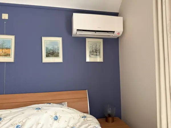 Wit airco-binnendeel boven het bed in een slaapkamer