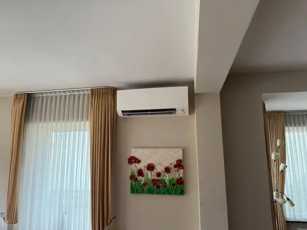 Wit airco-binnendeel boven een raam in een woonkamer