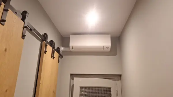 Wit airco-binnendeel in een hal met schuifdeur