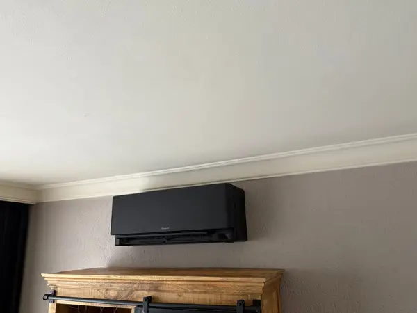 Zwart airco-binnendeel boven een houten wandplank