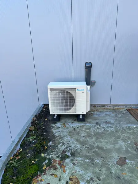 Buitenunit op wandbeugels naast een plat dak
