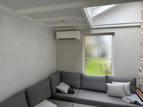 Wit airco-binnendeel in een woonkamer met hoekbank