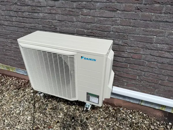 Buitenunit op een verhoging tegen een donkere gevel