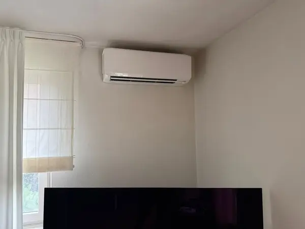 Wit airco-binnendeel boven een donker tv-paneel