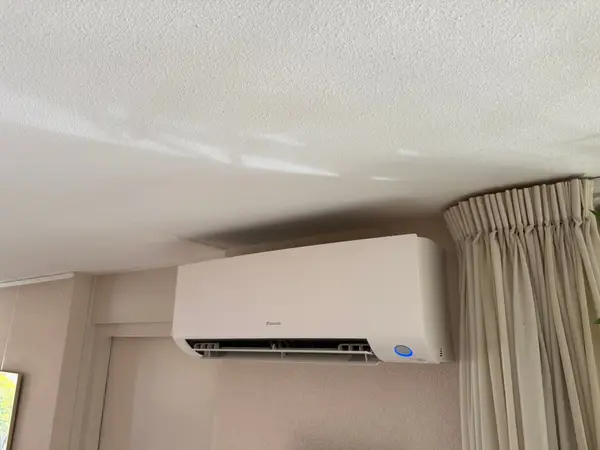 Wit airco-binnendeel naast het raam in een woonkamer