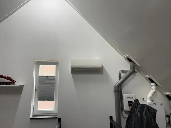 Wit airco-binnendeel hoog in de hoek van een kamer