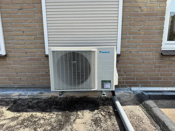 Buitenunit tegen een lichte gevelbekleding in de tuin