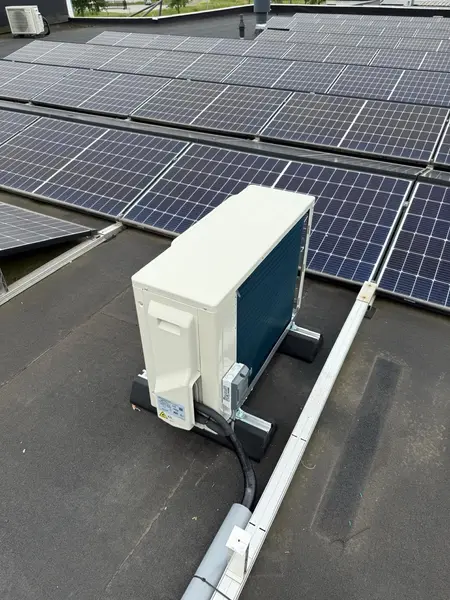 Plat dak vol zonnepanelen met airco-buitenunit, basis voor een thuisbatterij
